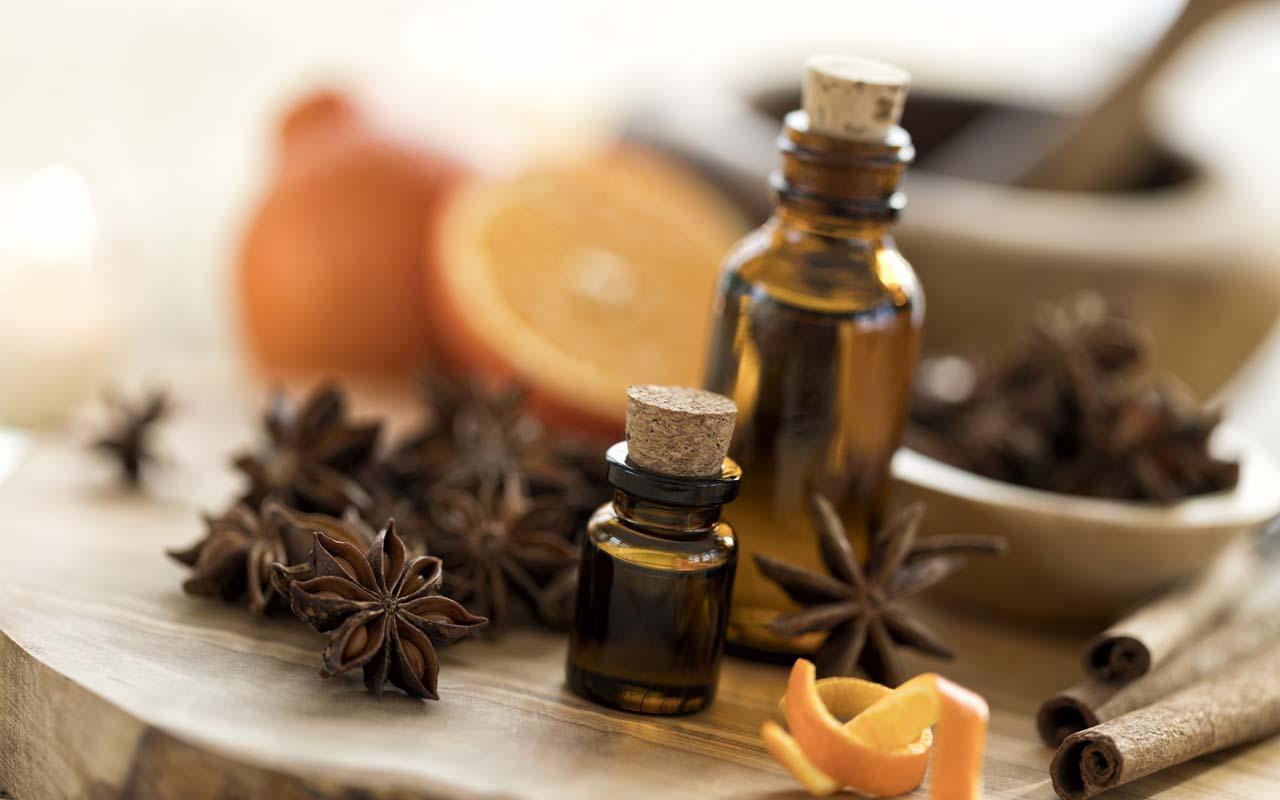 Non-branded essential oils on a table with orange slices and cinnamon sticks