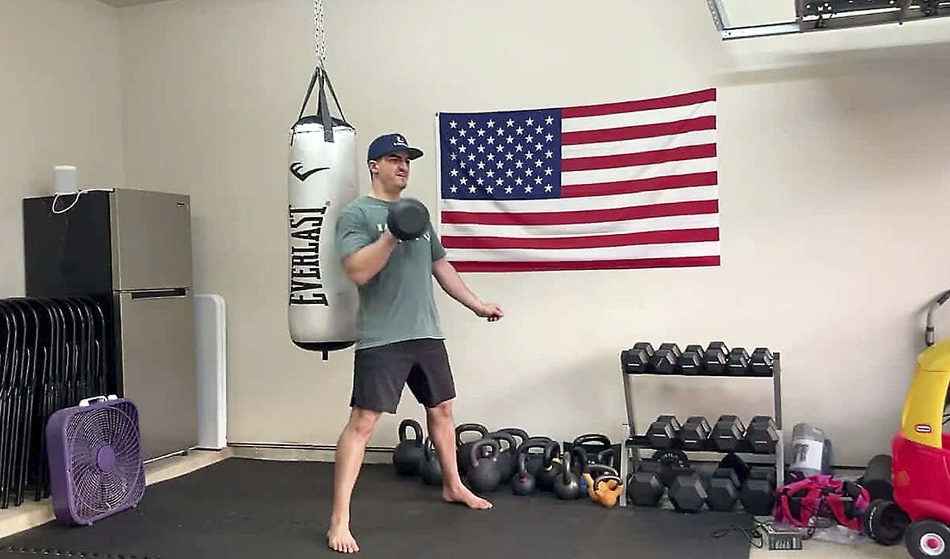 A man in a home gym uses a kettlebell.