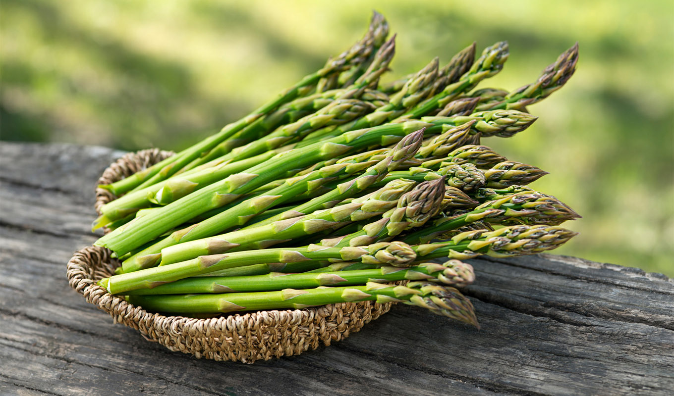 Bundle of fresh asparagus spears on a wooden surface, organic green vegetable rich in nutrients, ideal for healthy recipes and seasonal cooking.