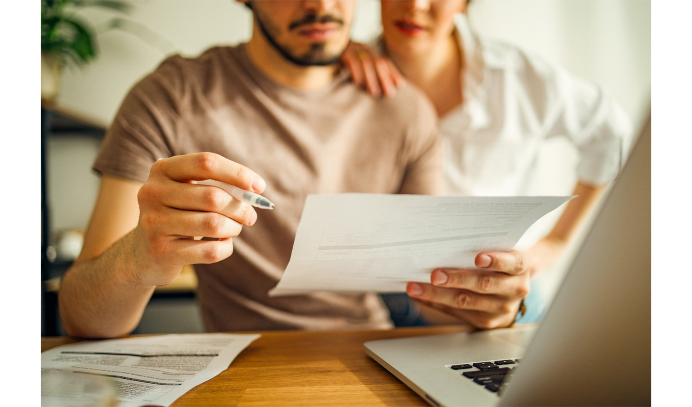 Husband and wife looking over bills by a computer.