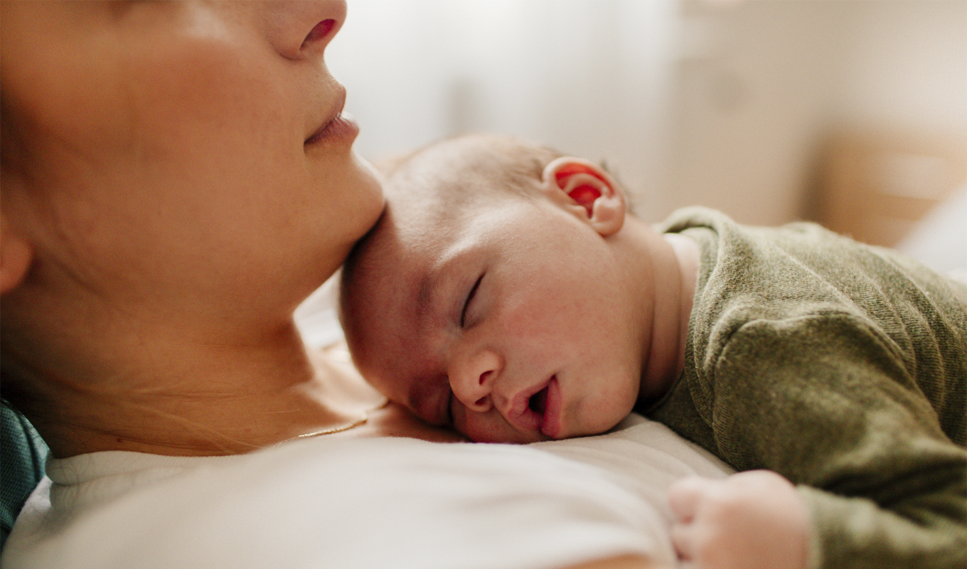 Baby sleeping on his mother's torso.