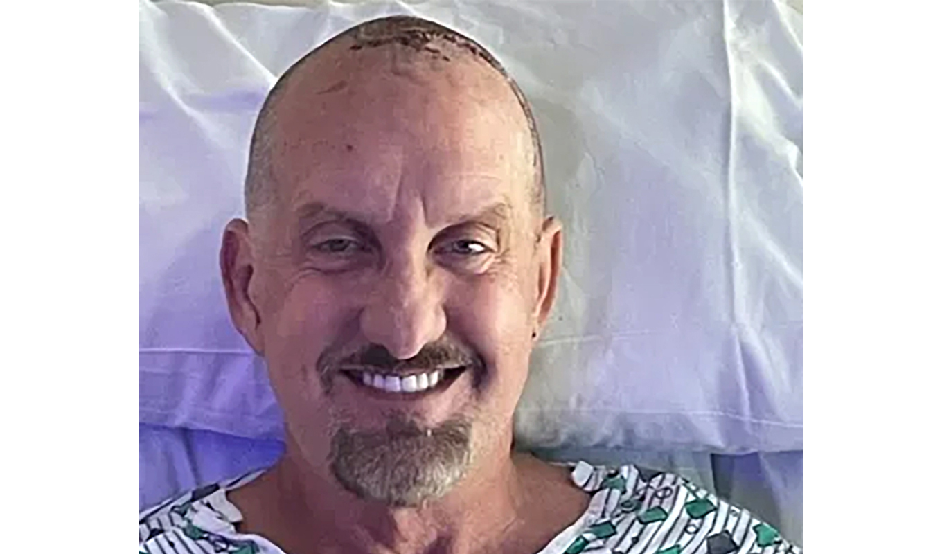 Smiling bald patient resting in hospital bed.