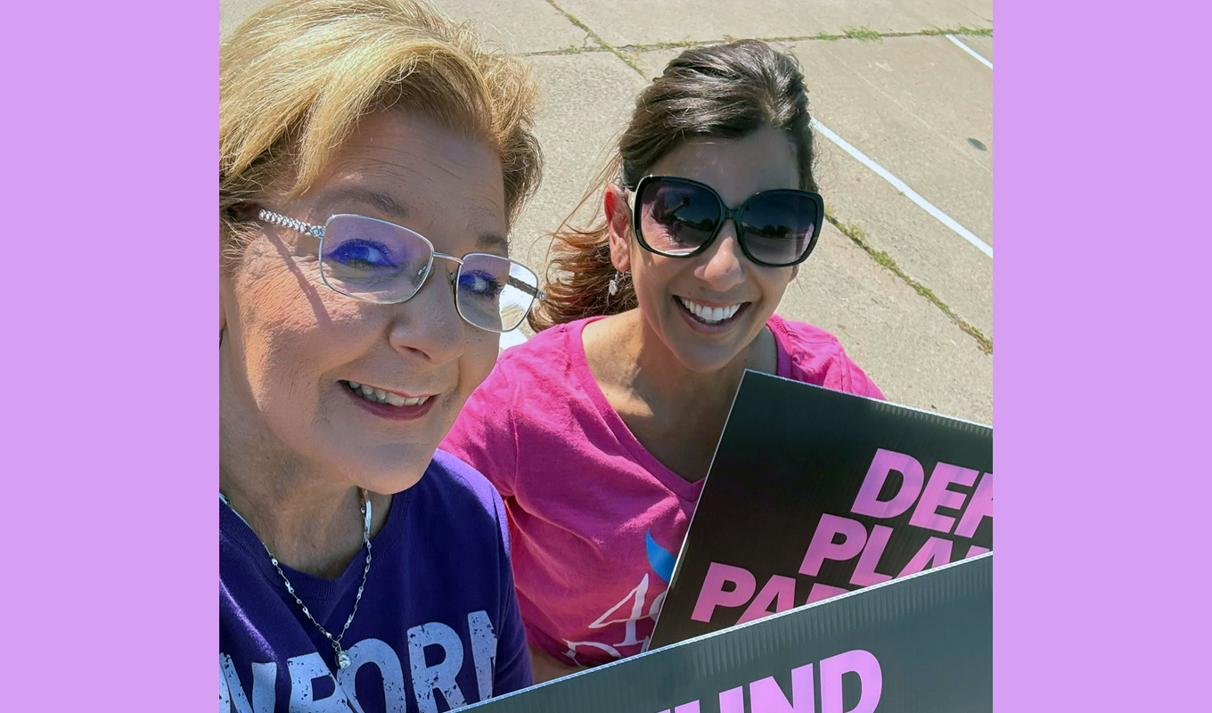 Two smiling women stand outside.