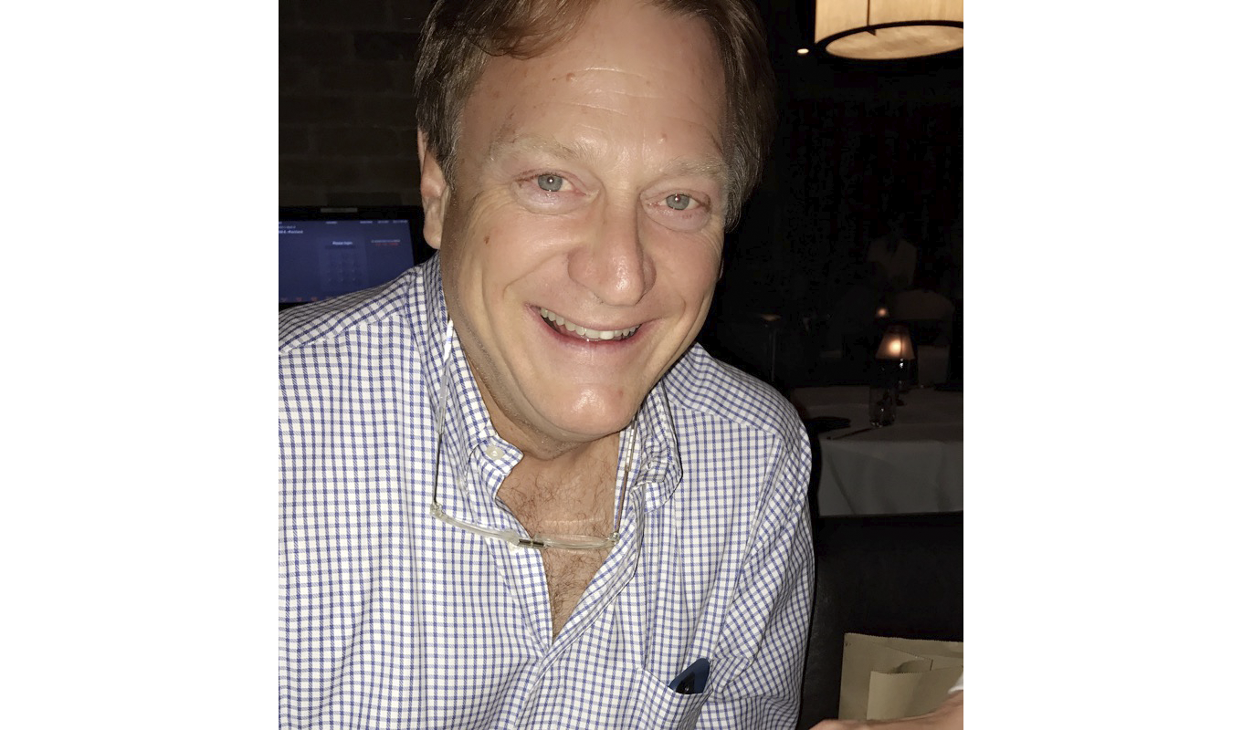Man in checkered shirt sits at table.