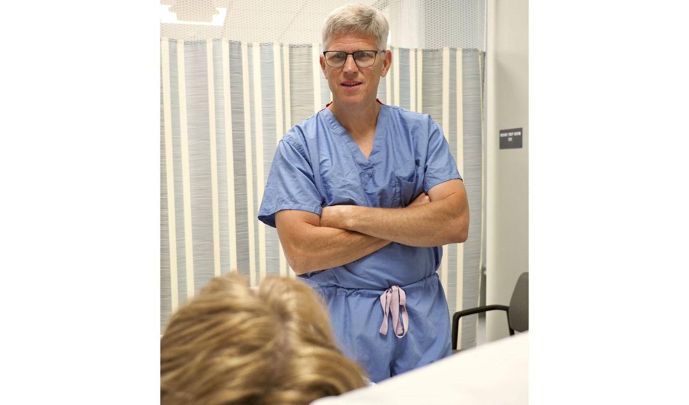 A doctor in scrubs talks to a patient.