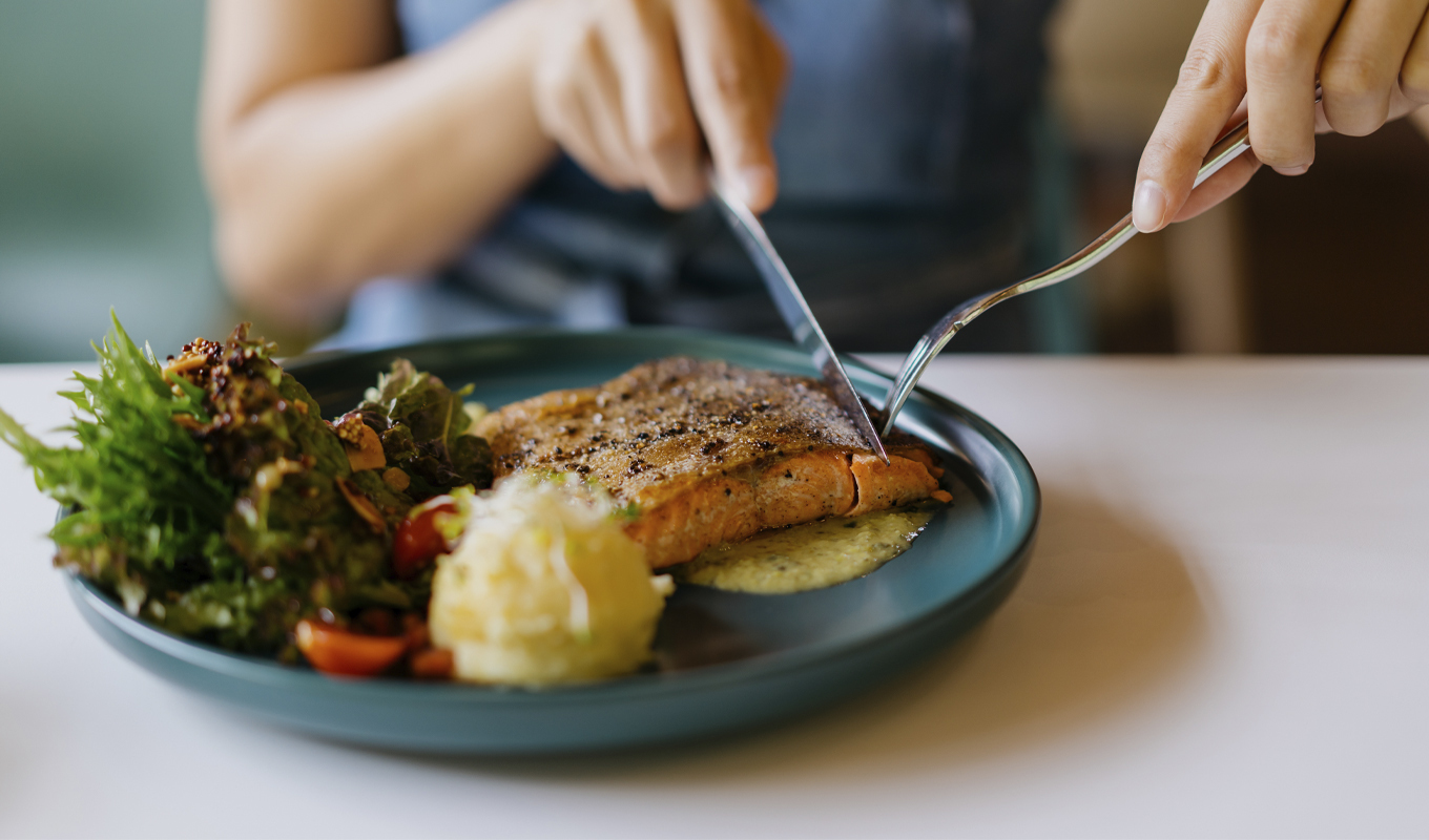 A person enjoying a delicious meal, using a fork and knife to savor each bite.