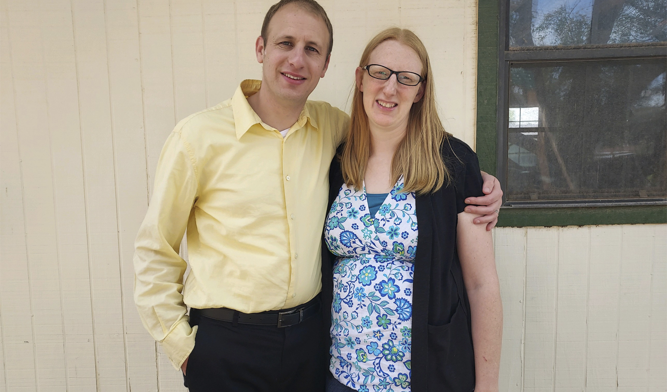 A husband and wife pose together, standing closely, with a warm and inviting atmosphere surrounding them.