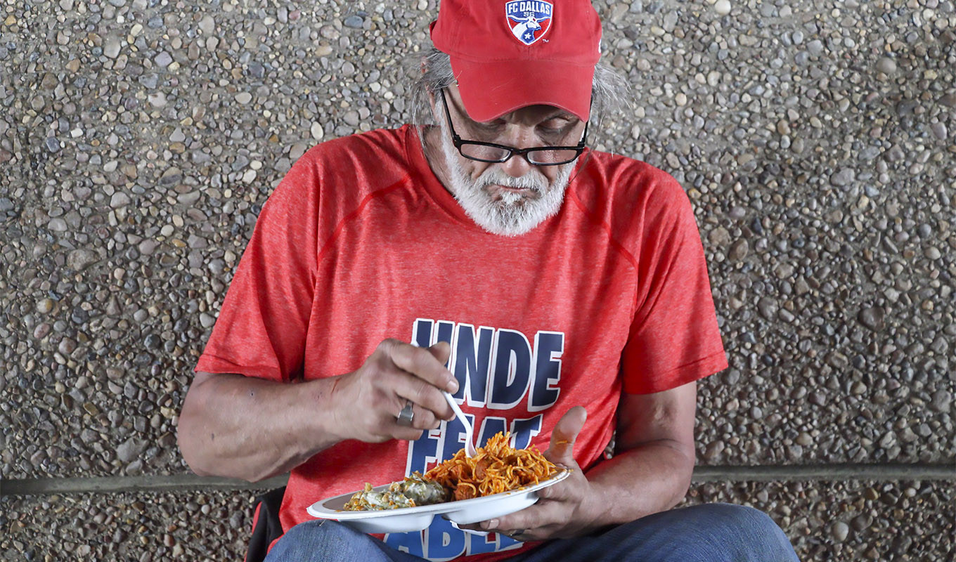 A beneficiary of  Bridges Beyond Hope enjoys a freshly cooked meal under an overpass in Houston.