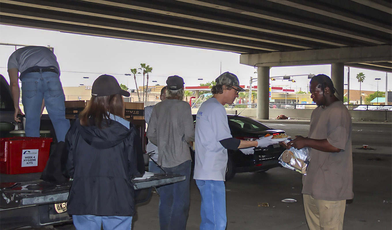 Volunteers with Hope Beyond Bridges serve meals to homeless people below an overpass in Houston.
