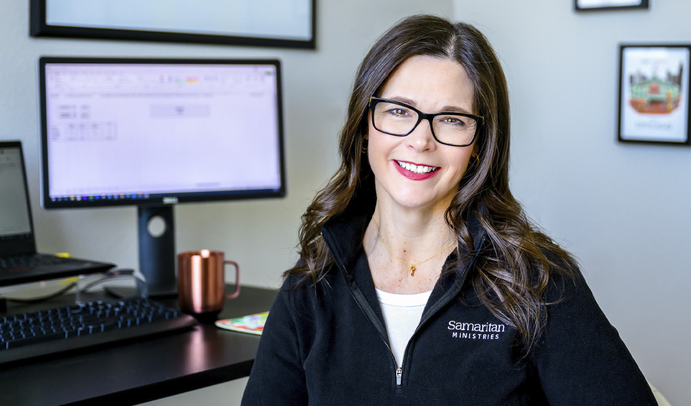 Smiling woman stands in front of office desk.