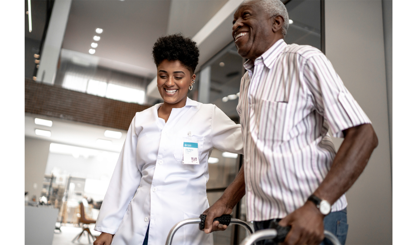 Elderly man being helped around by a nurse.