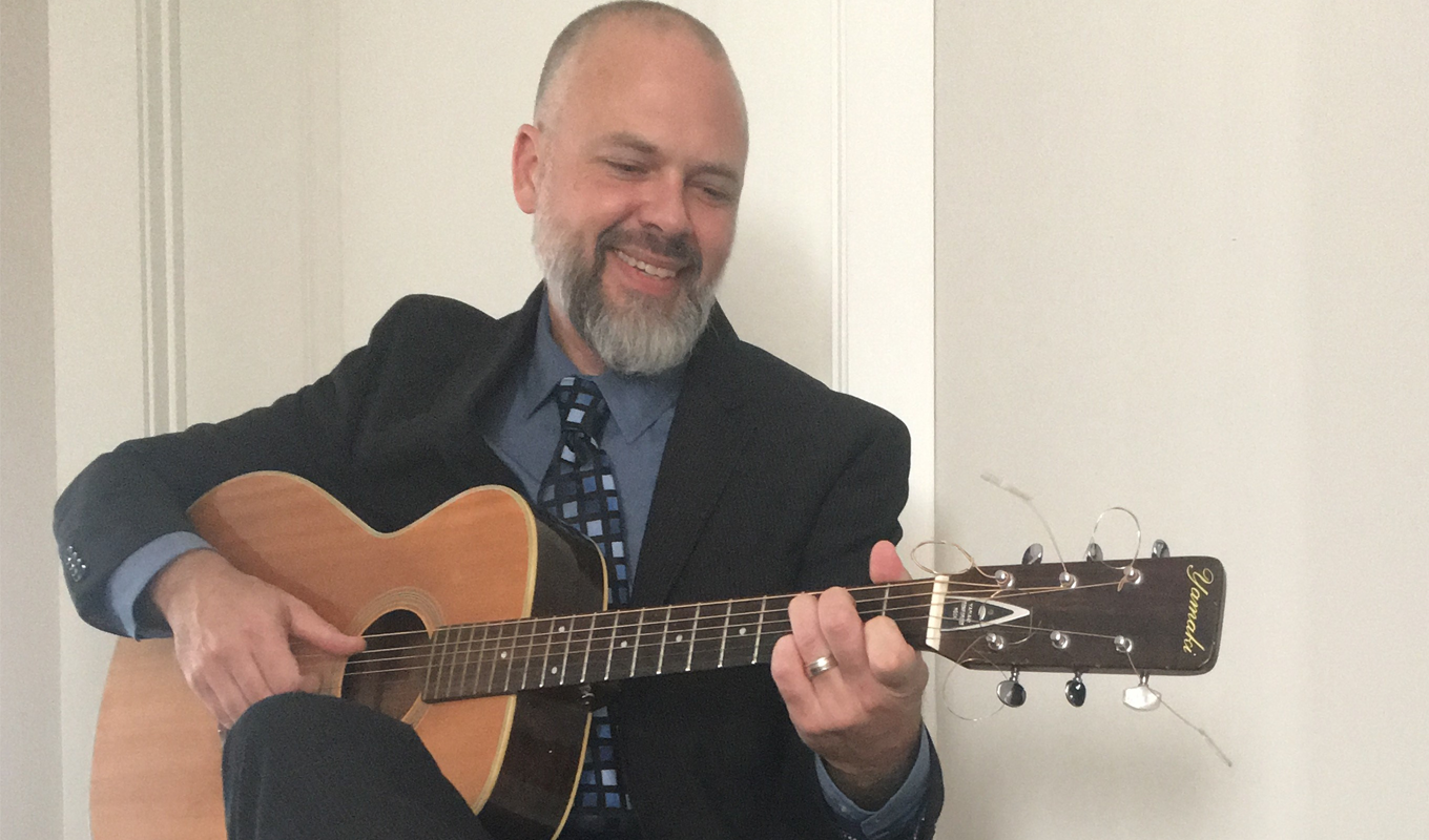 Matt Larson sits and plays guitar