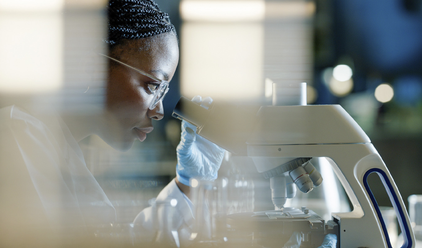 Woman peers into a microscope.
