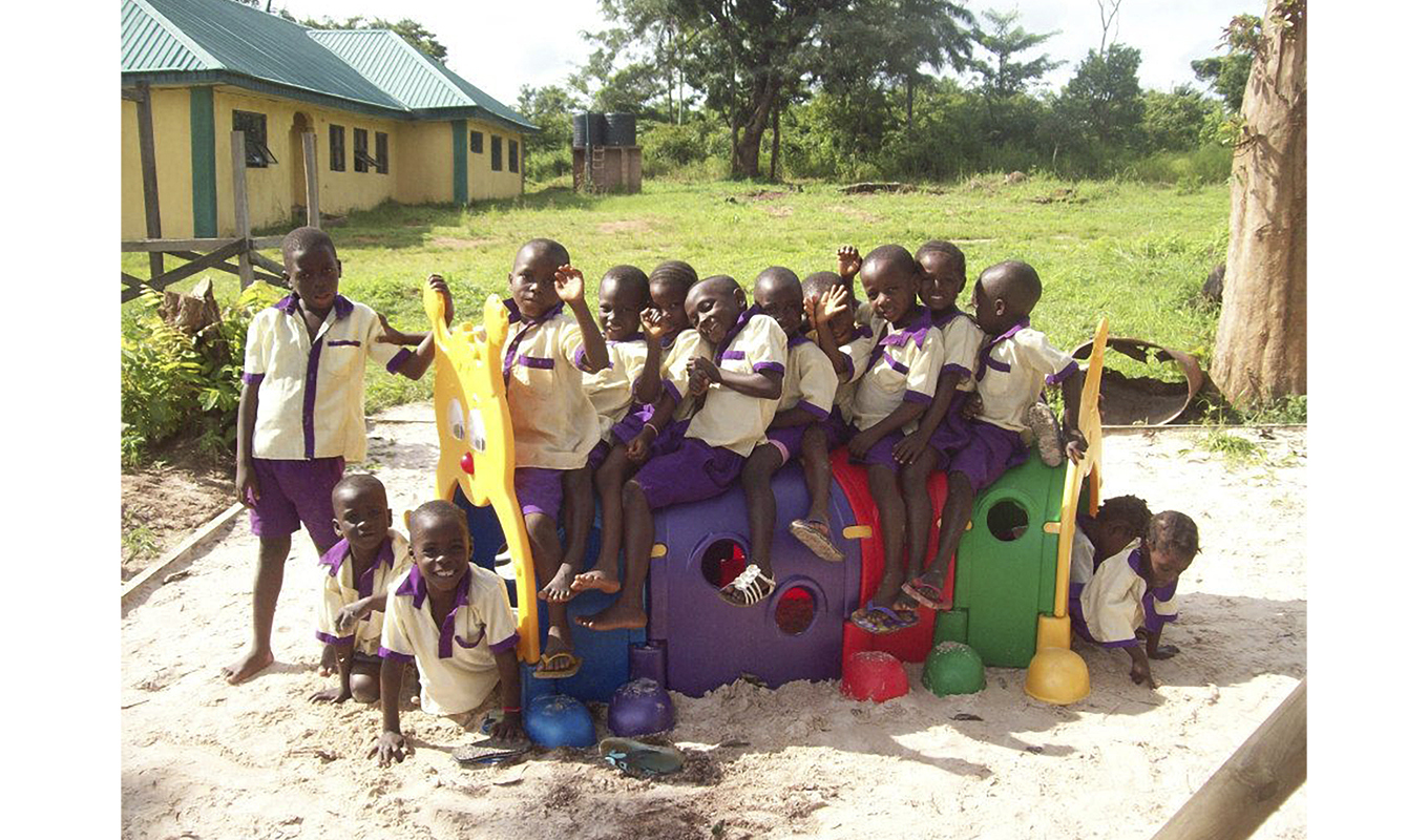 A group of children in school uniforms happily sitting together on a playground, enjoying their time outdoors.
