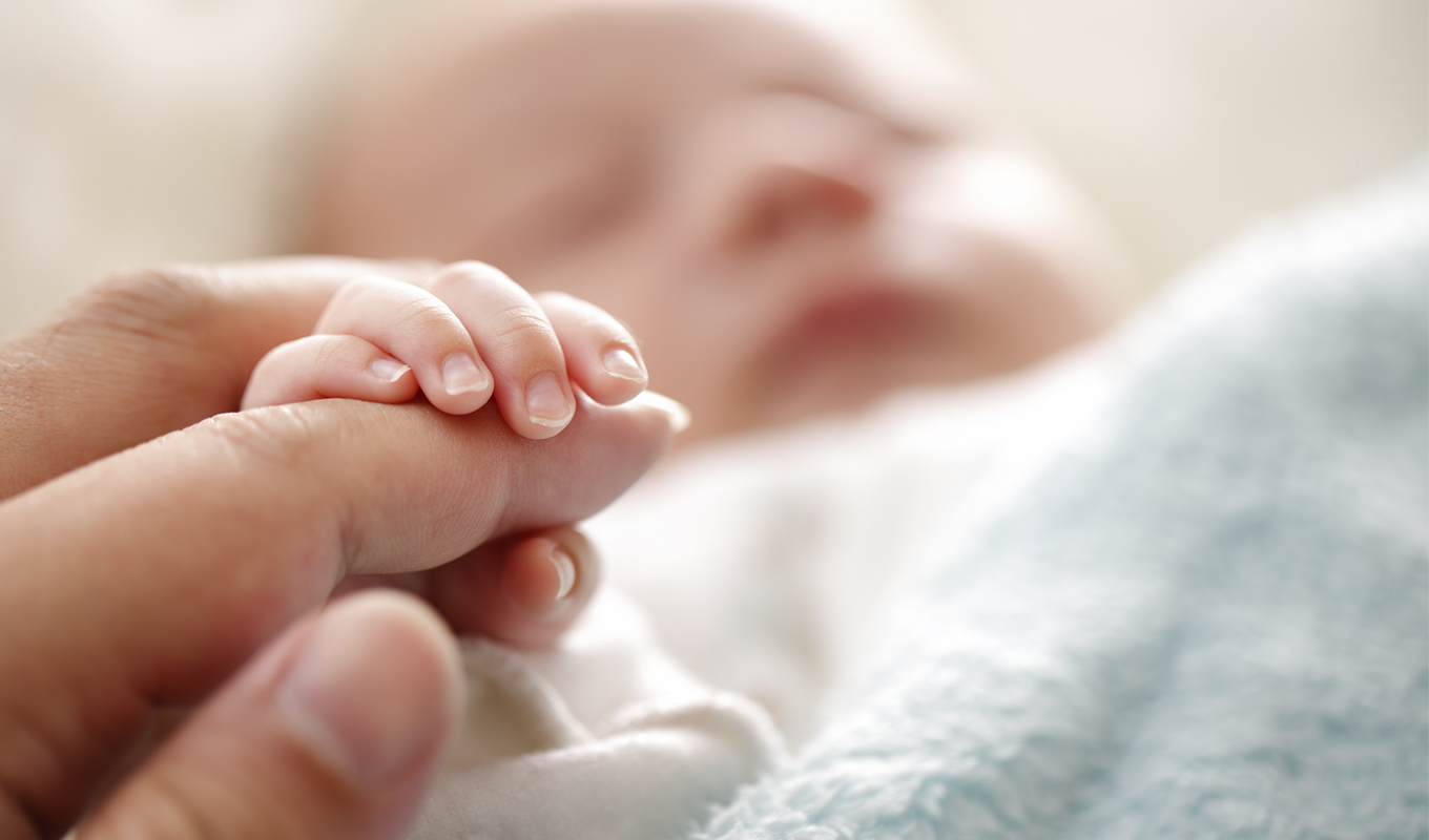 Infant holding a parent's finger