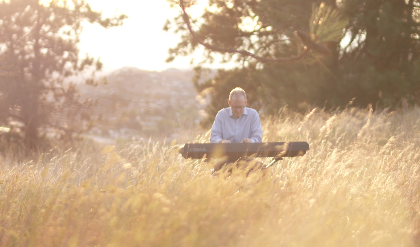 Stanton Lanier playing on an electric piano in an overgrown field