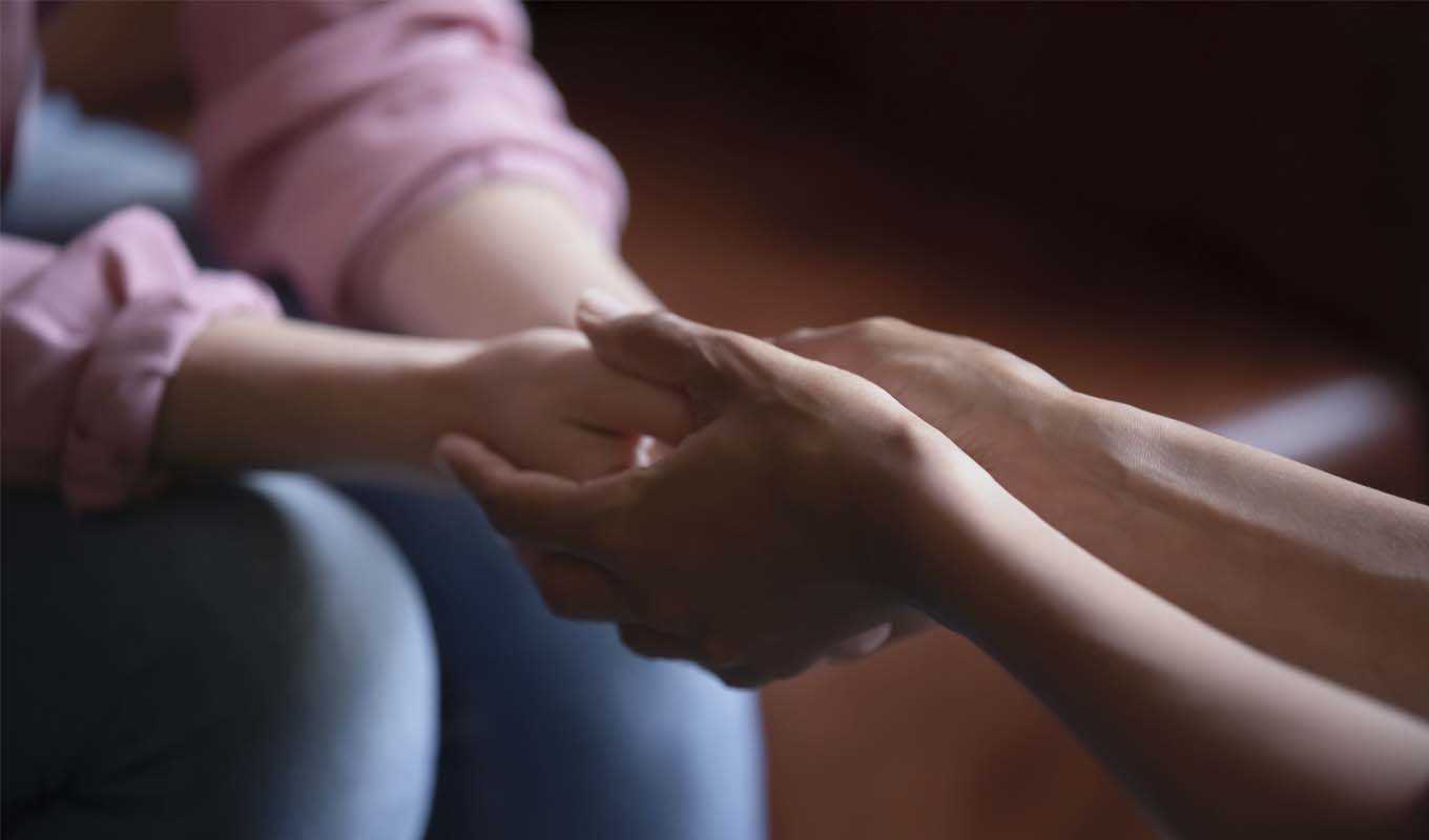 Two women comfortably holding hands