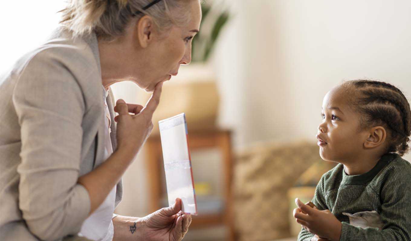 A woman teaching a young girl speech techniques