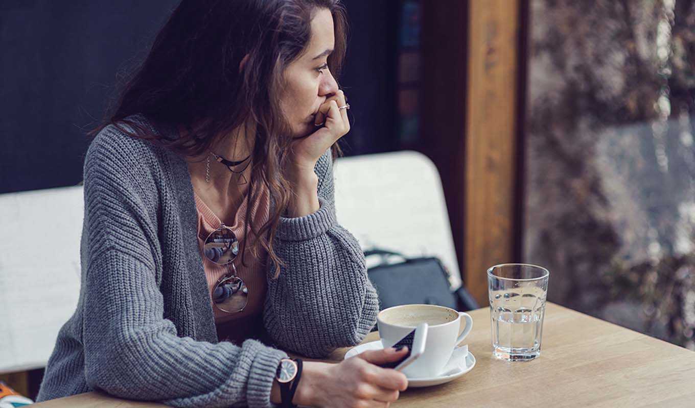 A worried woman sitting in a coffee shop booth, alone