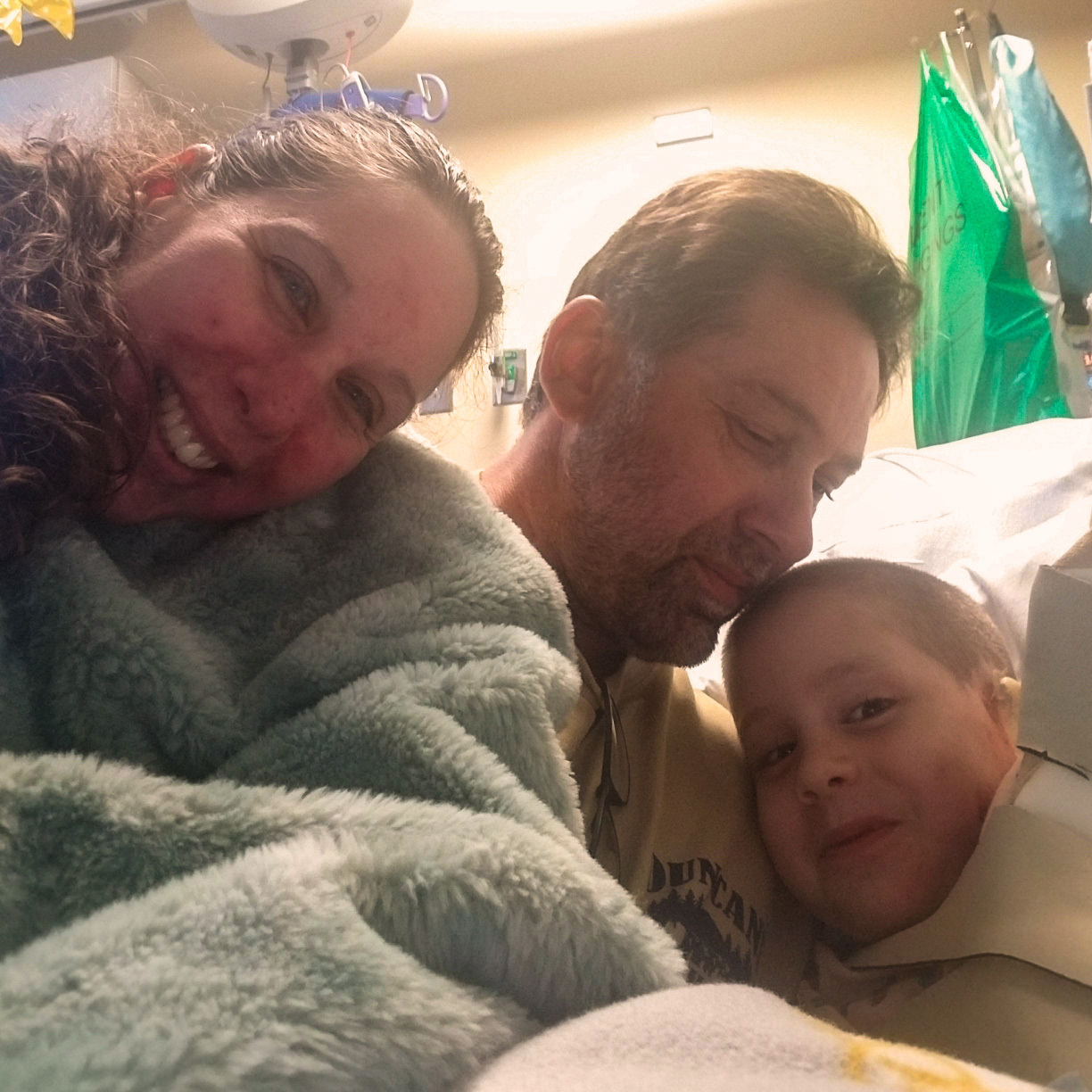 The Olsons hugging in the hospital bed.